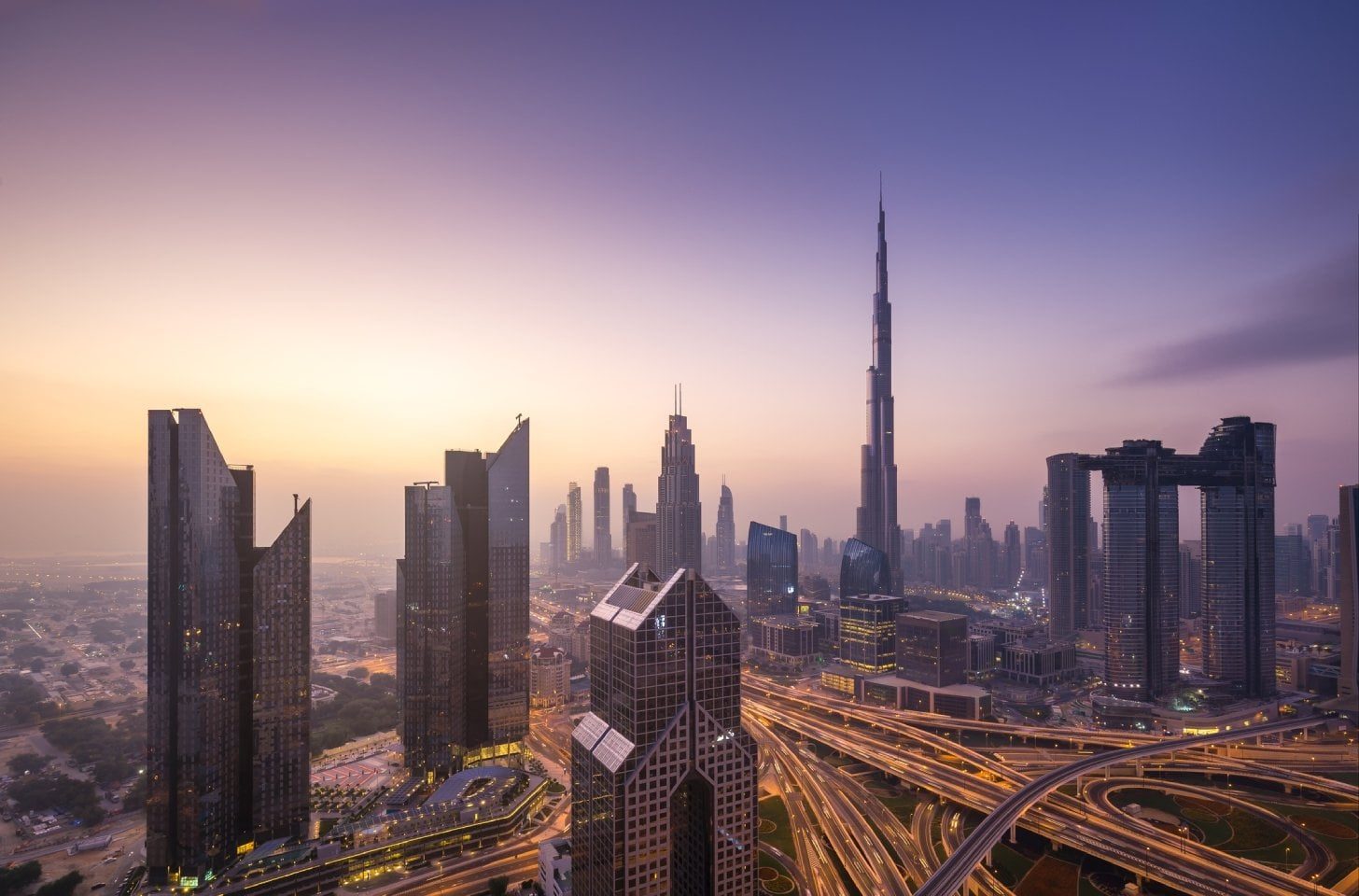 Dubai skyline at sunset with Burj Khalifa visible among surrounding skyscrapers