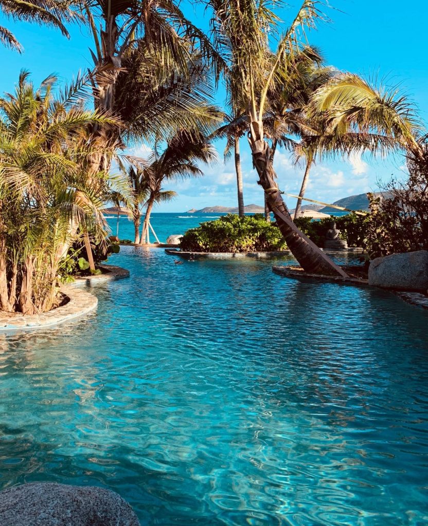 Tropical pool surrounded by palm trees on Necker Island overlooking the Caribbean Sea