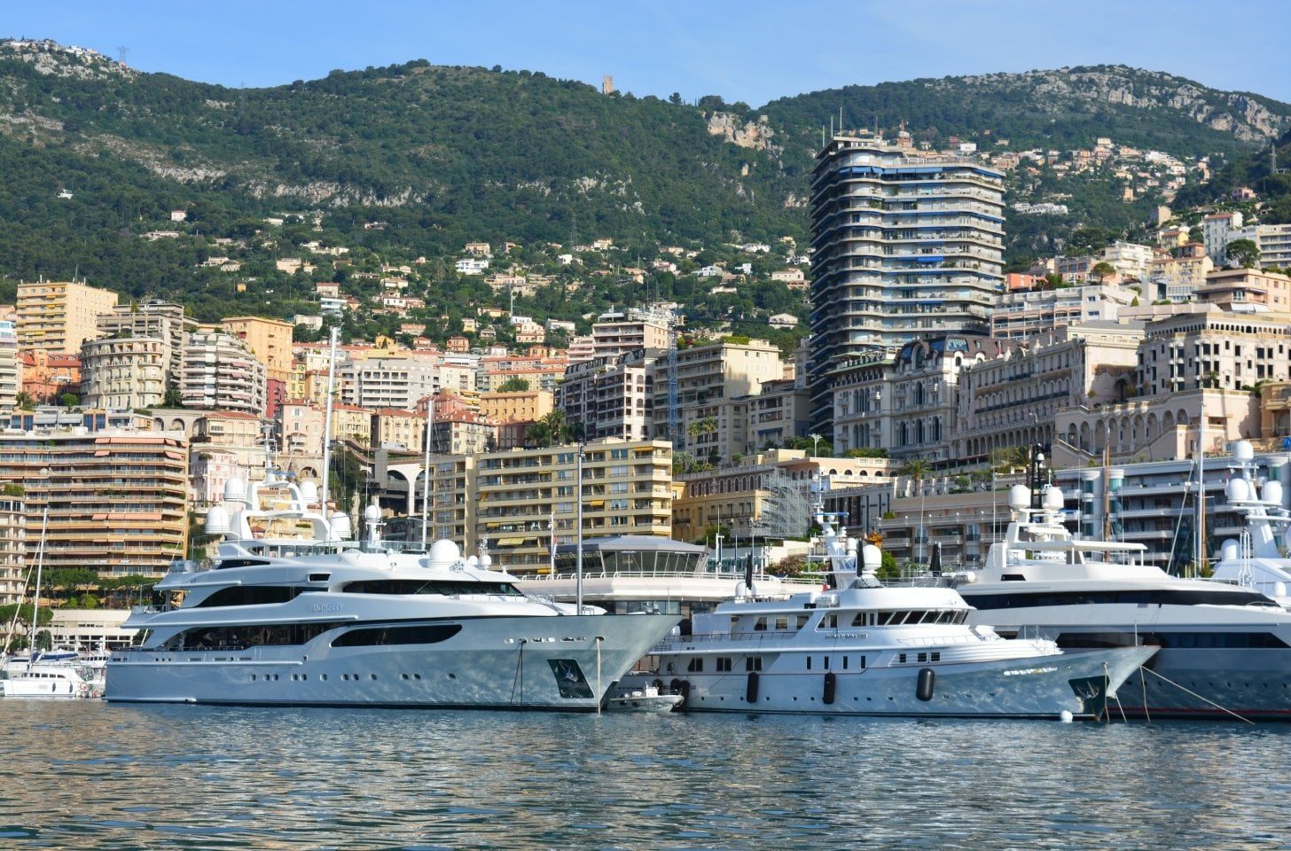 Luxury yachts moored in Monaco’s Port Hercules with city skyline backdrop