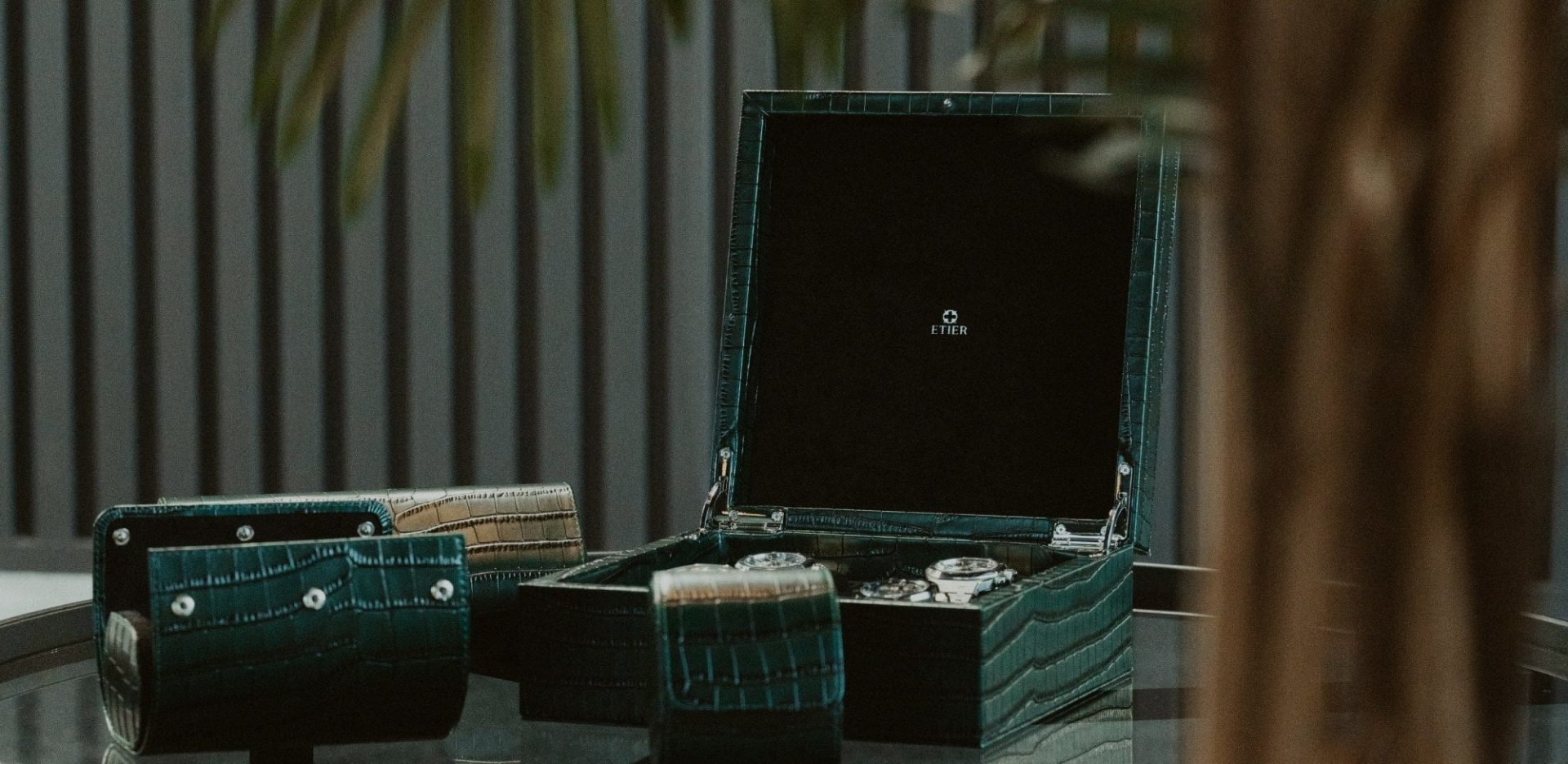 Green crocodile-embossed leather watch box and travel accessories styled indoors