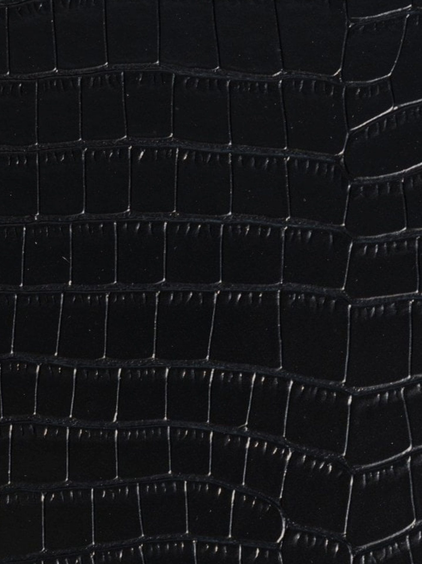 Close-up detail of black crocodile-embossed leather texture