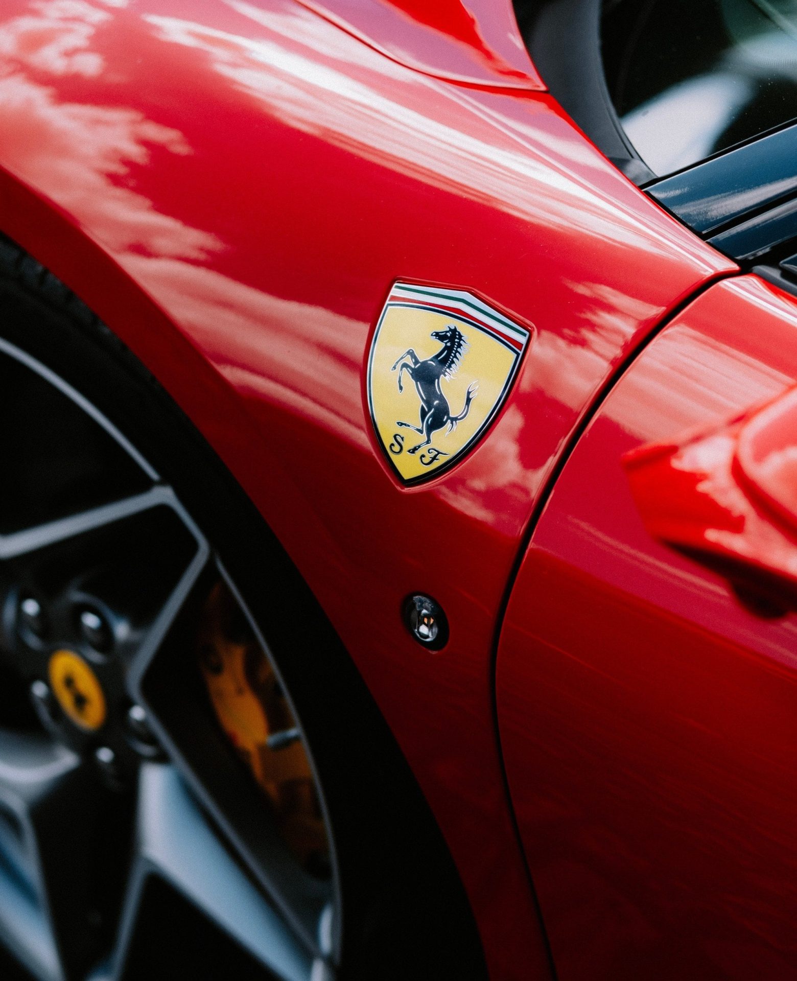 Close-up of Ferrari badge on red supercar bodywork