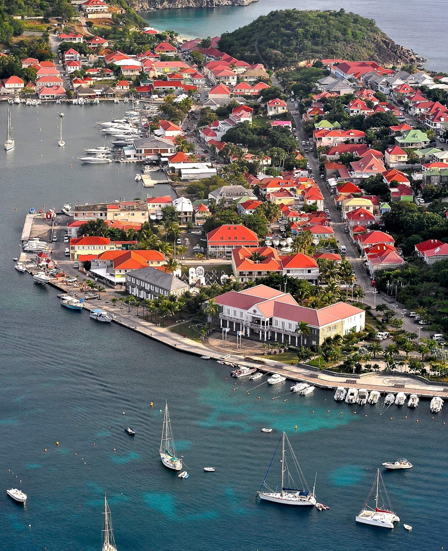 Aerial view of Gustavia Harbour in St Barths, featuring luxury yachts, turquoise waters and red-roofed island buildings