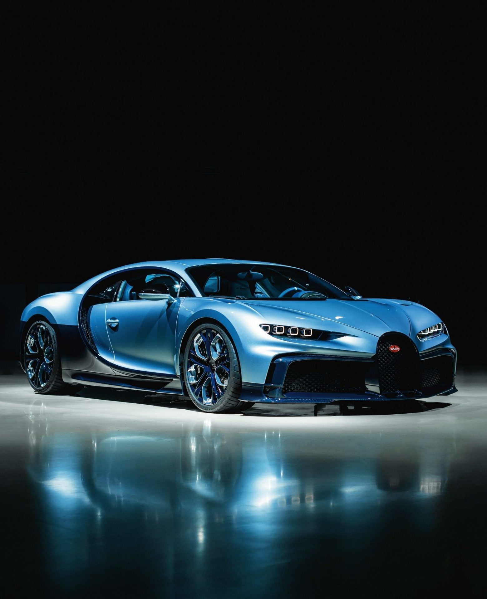 Blue Bugatti sports car shown from a front three quarter angle against a dark studio background