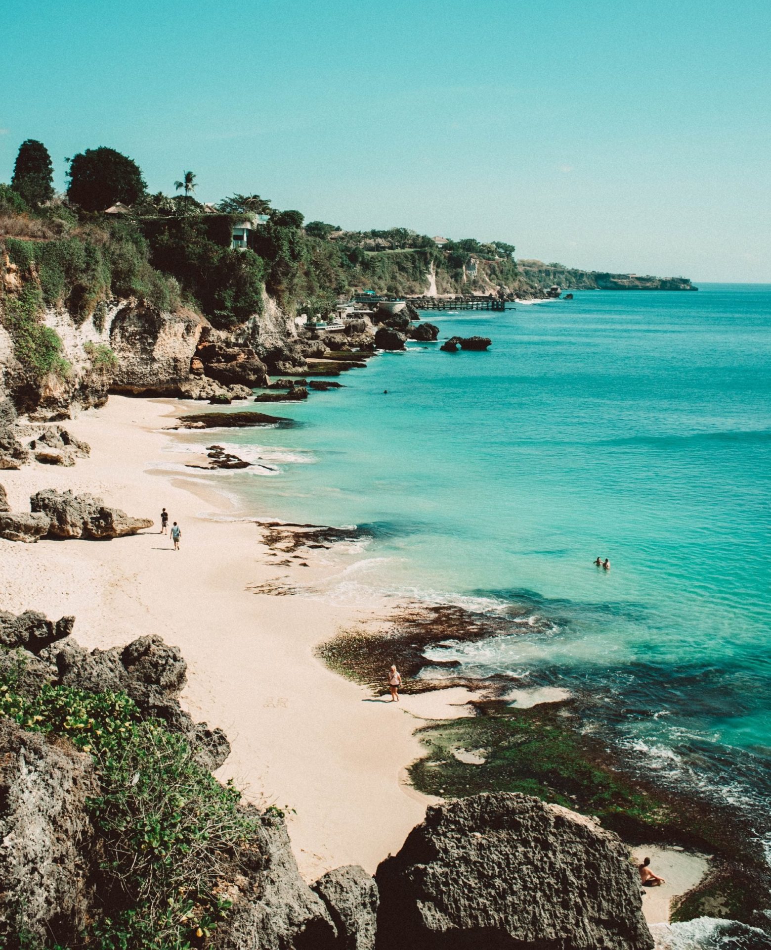 Cliffside beach in Bali with turquoise water, rocky shoreline and sandy cove