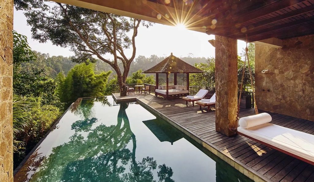 Jungle pool in Bali surrounded by trees, wooden decking and stone architecture