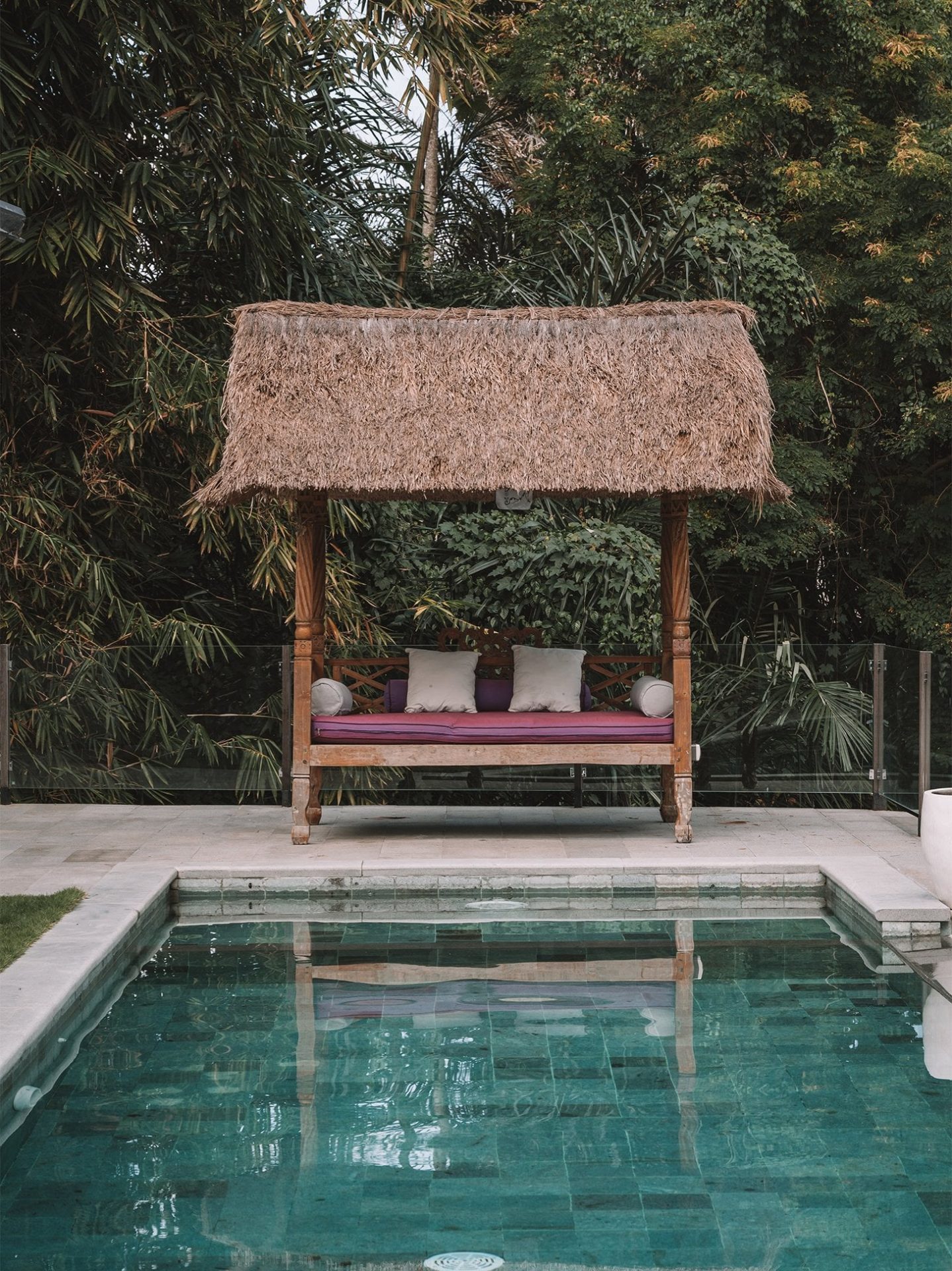 Traditional Balinese pavilion beside a pool surrounded by tropical vegetation
