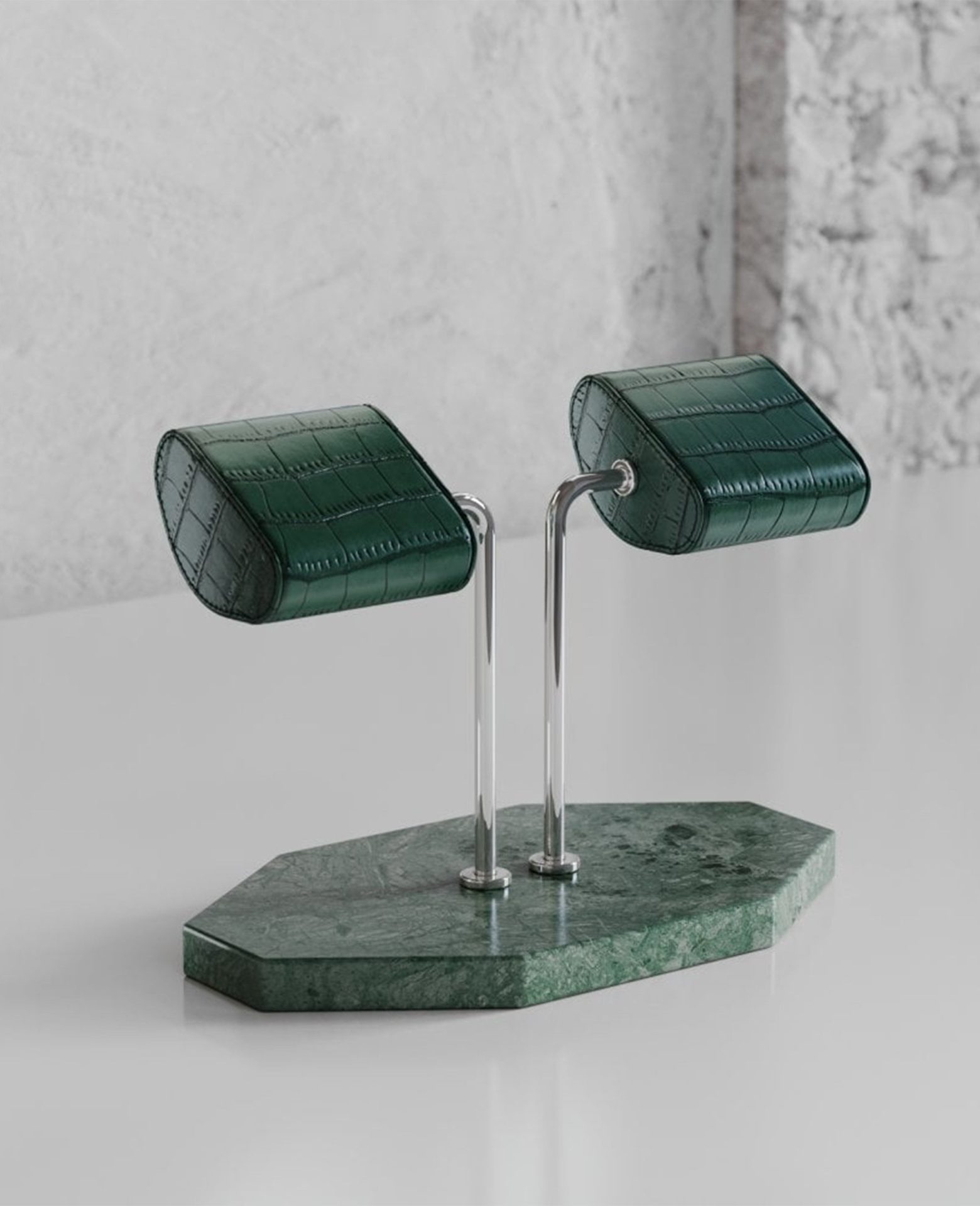 Luxury watch display stand featuring green leather cushions and a polished marble base