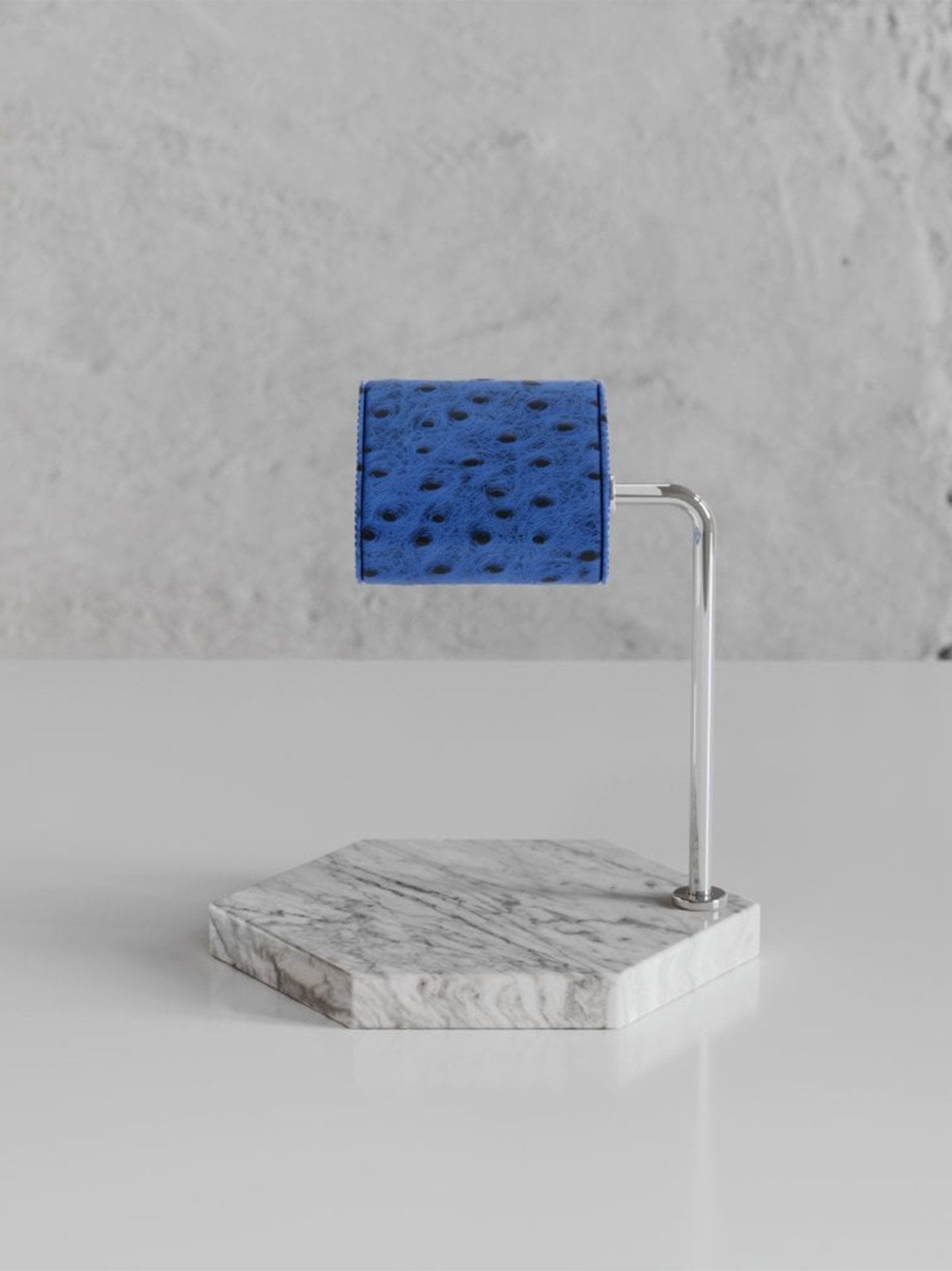 Luxury watch display stand with blue leather cushion and white marble base in a minimalist setting